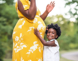 Portrait of a African American Pregnant Woman with her toddler touching her belly