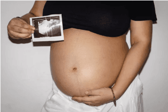 young pregnant women showing her sonogram in front of her belly