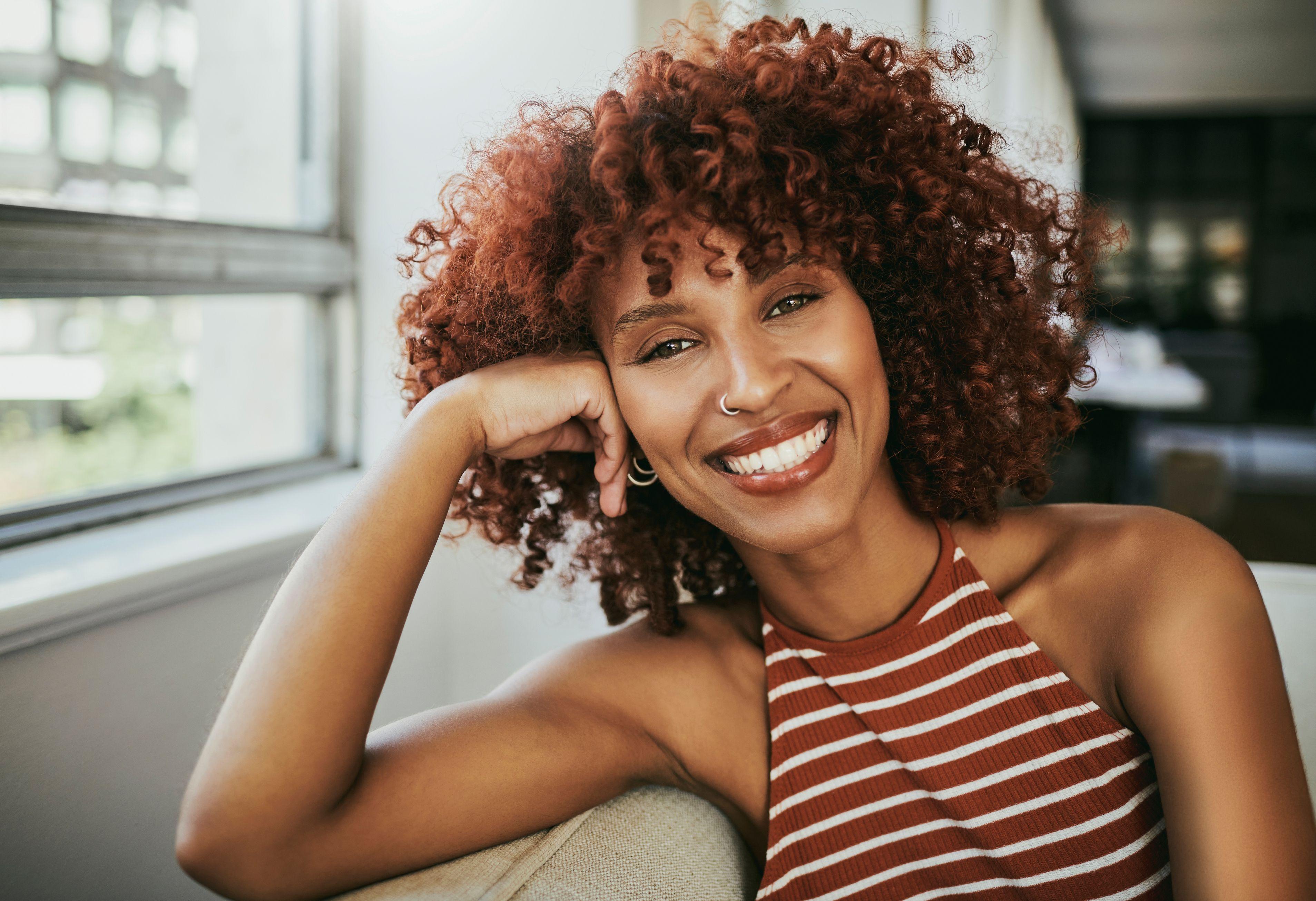 Relax, portrait and smile of Danielle on sofa in home in comfortable living room